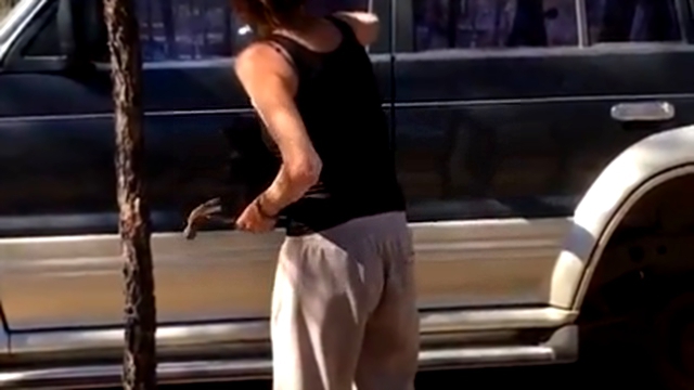 Женщина пытается молотком разбить стекло незапертого автомобиля